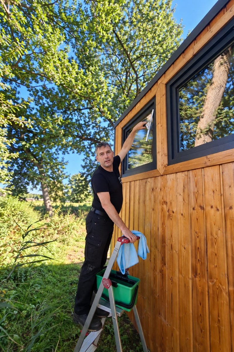 Fensterreinigung am Tiny House in Fitzen – Mitarbeiter von Witzling Dienstleistungsservice bei der Glasreinigung mit Abzieher